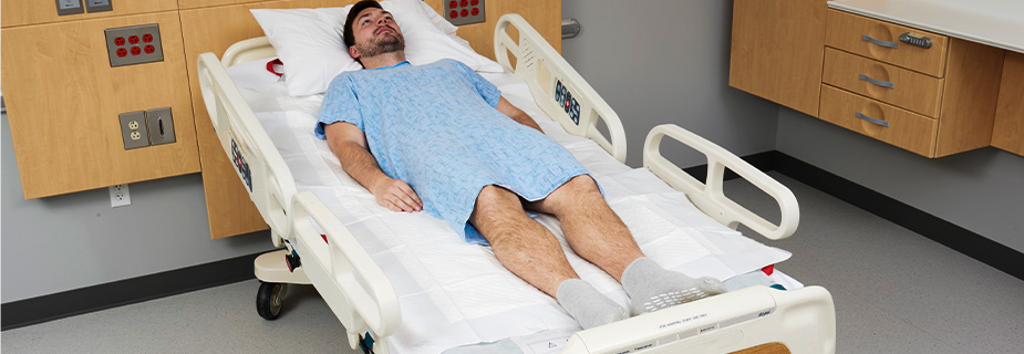 Patient lying in a hospital bed on top of a HoverCover Disposable Sheet